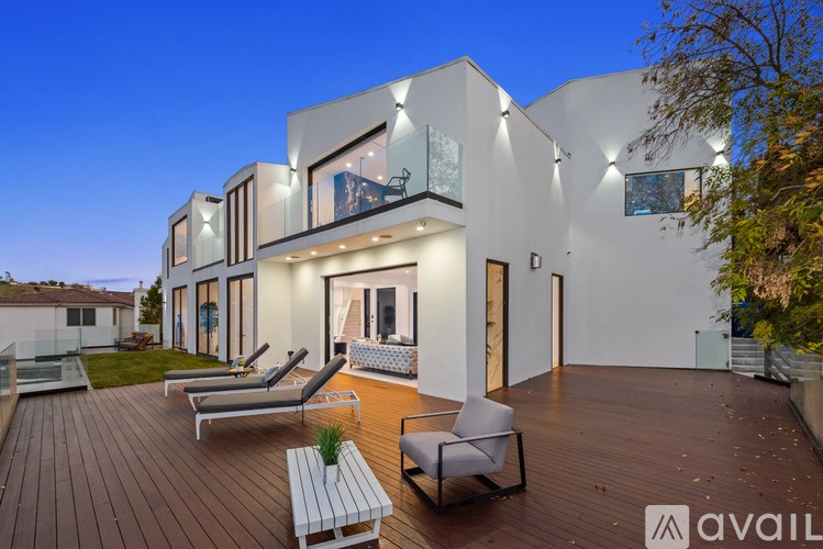 A modern house with a wooden deck and lounge chairs.