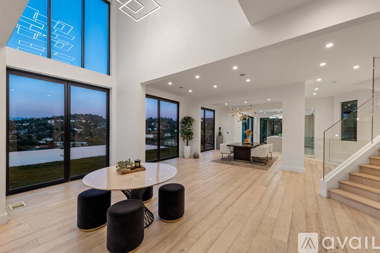 A spacious living room with a high ceiling and a view of the city through the windows.