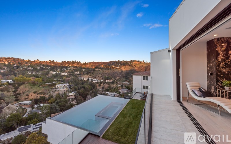 A modern house with a glass roof and a view of the hills.