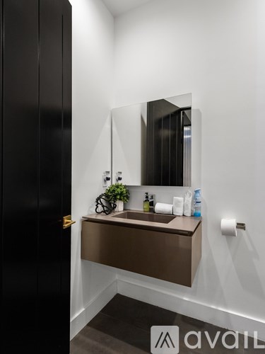 A bathroom with a sink, mirror, and a plant.