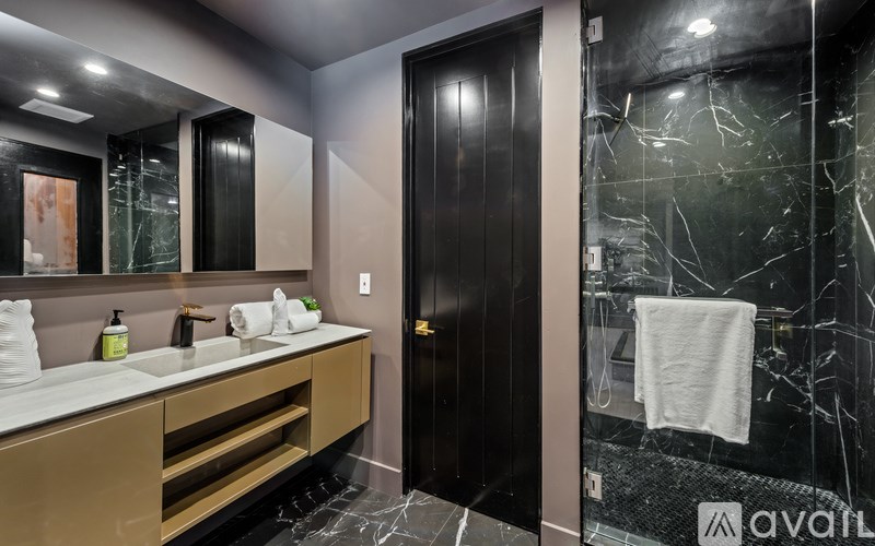A bathroom with a sink, mirror, and a black door.