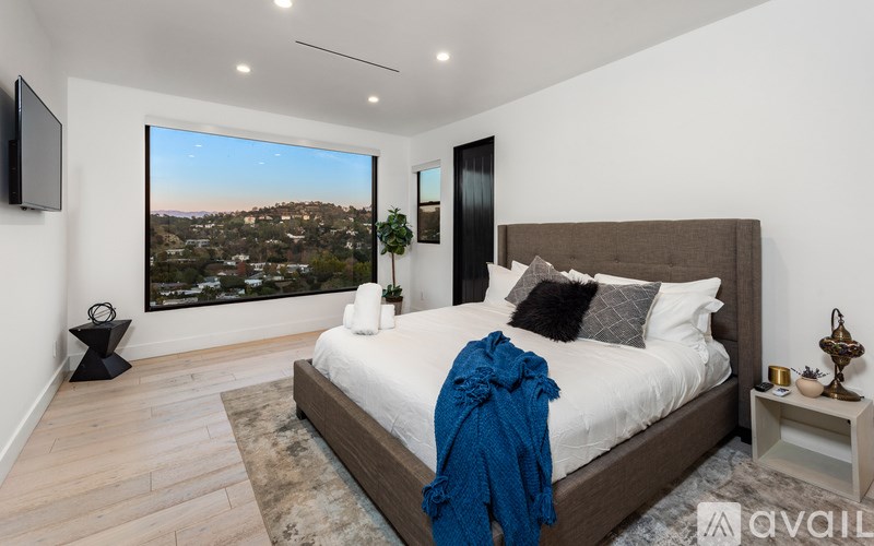 A bedroom with a large bed and a television on the wall.