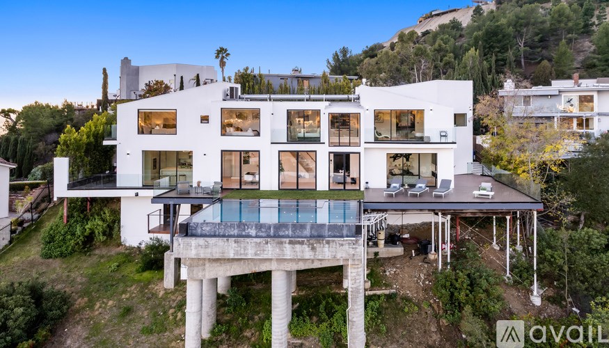 A modern white house with a pool in the middle of the backyard.