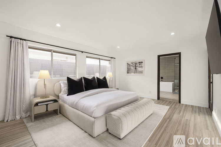 A bedroom with a large bed and a window with curtains.