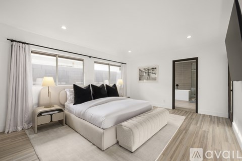 A bedroom with a large bed and a window with curtains.