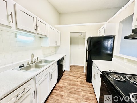 A kitchen with white cabinets and a black refrigerator.