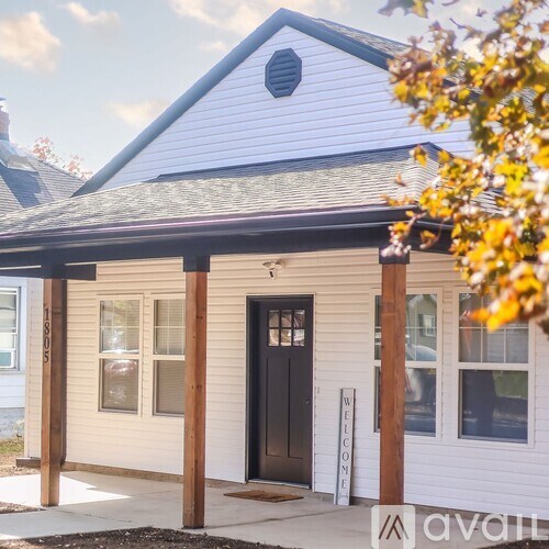 A small white house with a black door and a sign that says "welcome".