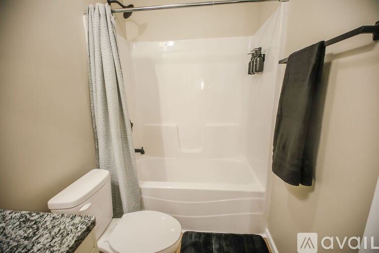 A bathroom with a toilet, a bathtub, and a towel hanging on the wall.