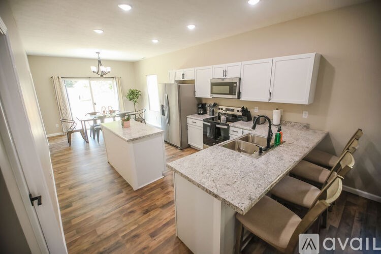 A kitchen with a white counter top and wooden floors.