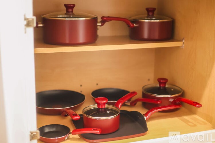 A kitchen cabinet with red cookware.