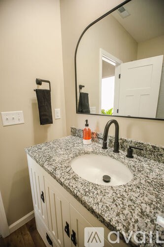 A bathroom sink with a granite counter top and a mirror above it.