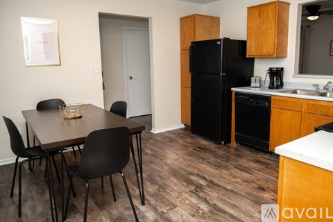A kitchen with a black fridge and wooden cabinets.