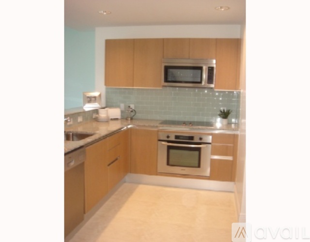 A kitchen with wooden cabinets and a stainless steel microwave above the stove.
