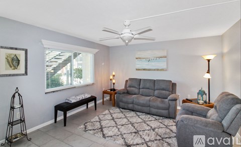 A living room with a grey couch and a black and white rug.