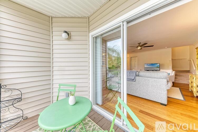 A balcony with a green table and a fan in the room.
