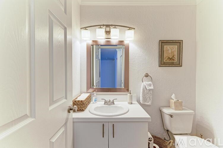 A white bathroom with a sink, mirror, toilet, and a door.