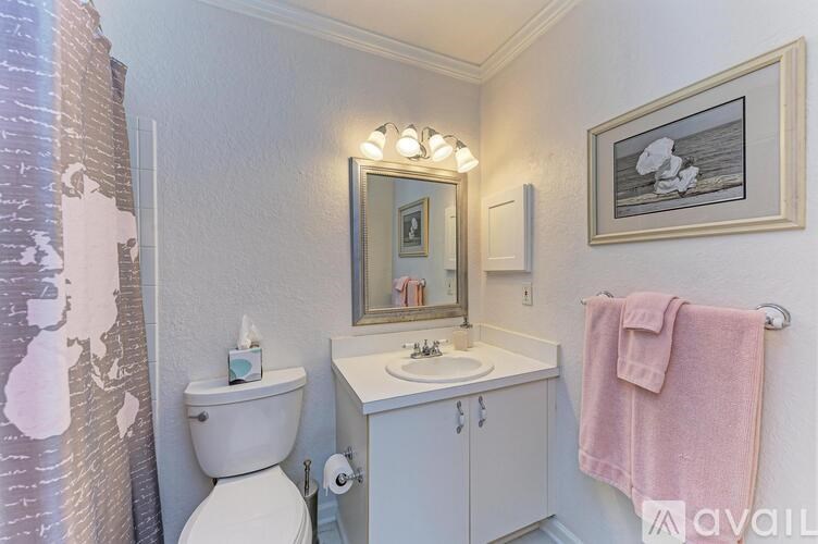 A bathroom with a toilet, sink, mirror, and a pink towel.