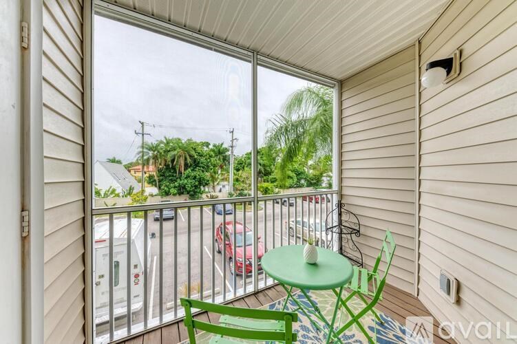 A balcony with a table and chairs overlooking a parking lot.