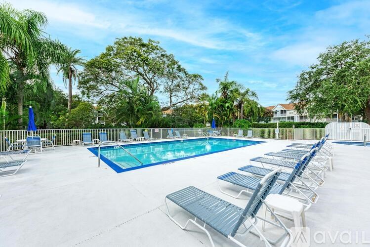 A large outdoor pool surrounded by sun loungers and trees.