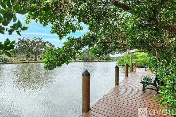 A wooden dock with a bench and a tree branch over it.