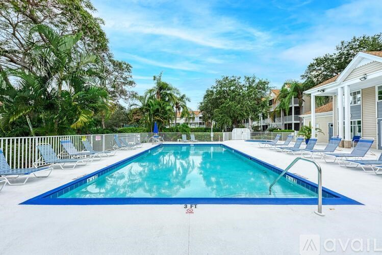 A large swimming pool surrounded by lounge chairs and trees.