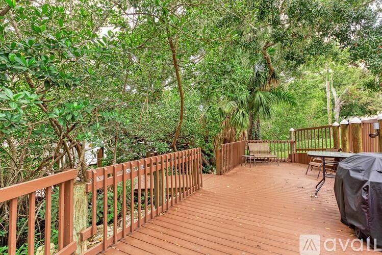 A wooden deck surrounded by greenery with a table and chairs.