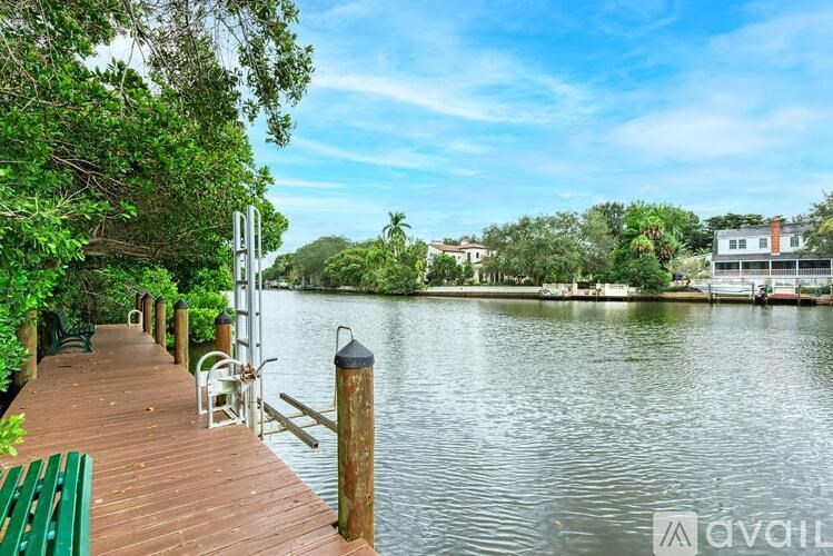 A wooden dock extends into a calm body of water surrounded by lush greenery.