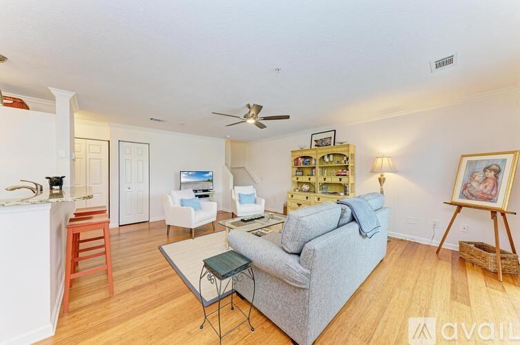 A living room with a grey couch, a wooden chair, a small table, and a painting on the wall.