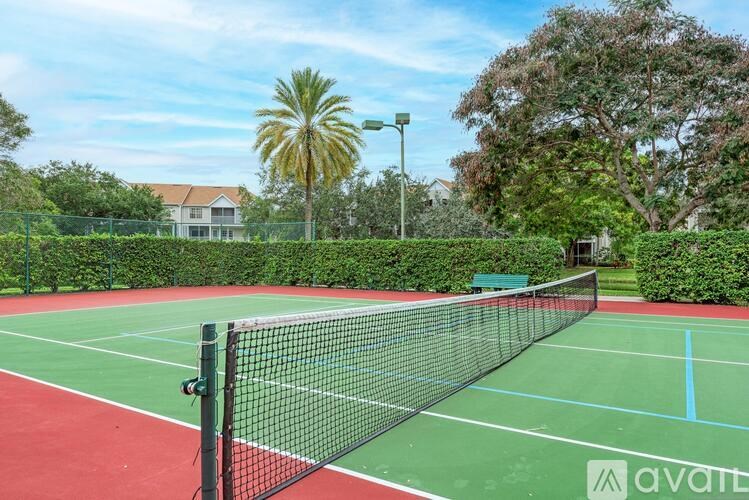 A tennis court with a net and a green and red surface.