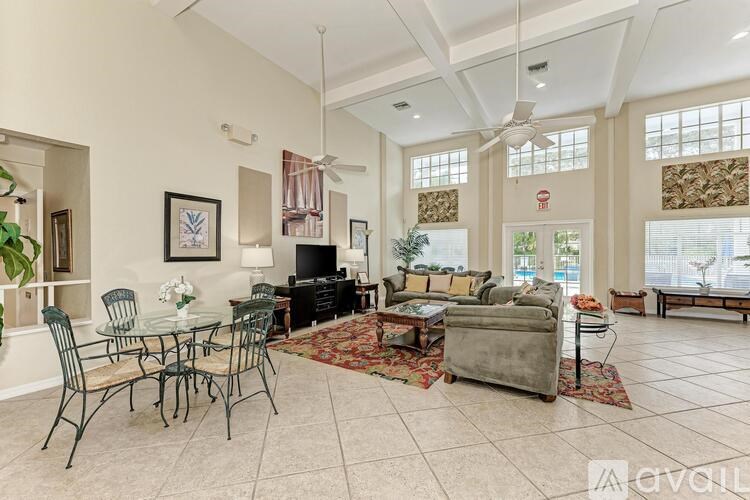 A living room with a glass table and chairs, a couch, and a television.