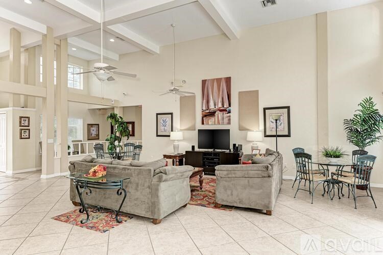 A living room with a grey couch, a television, and a potted plant.