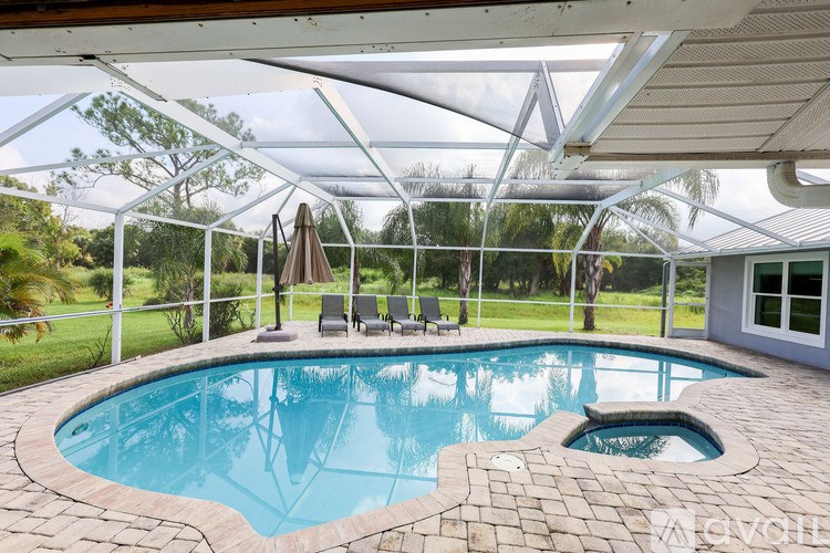 A pool with a stone border and a white umbrella.