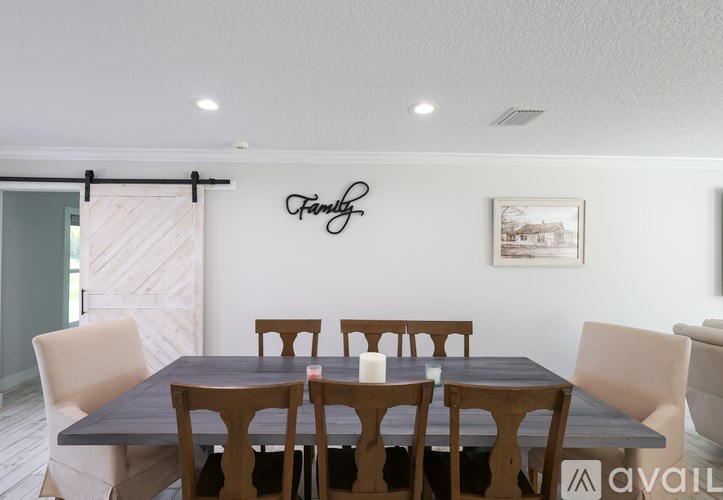 A dining room with a table and chairs and a family sign on the wall.