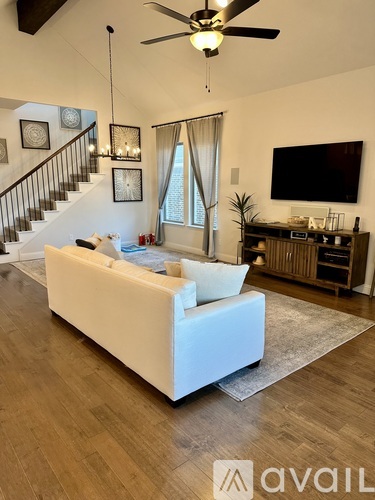 A living room with a white couch and a staircase.