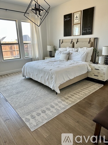 A bedroom with a large bed, a chandelier, and a window overlooking a balcony.