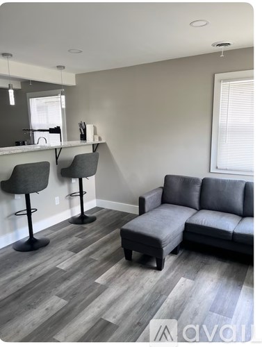 A grey couch and two chairs are in a room with wooden flooring.