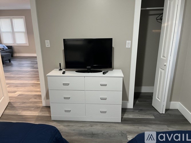 A black television sits on top of a white cabinet with three drawers.