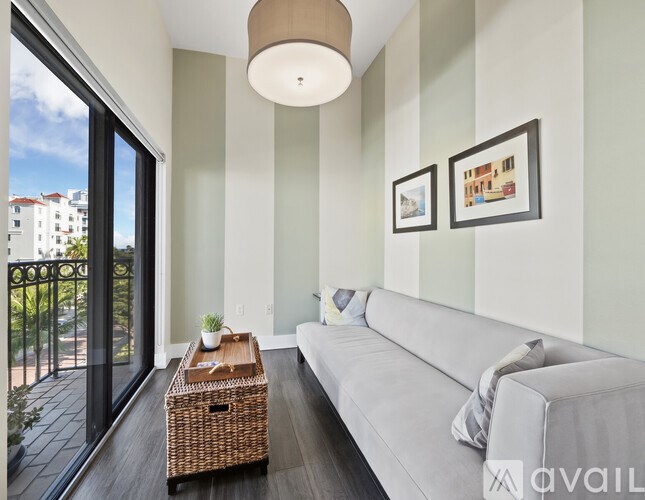 A living room with a grey couch, a wicker table, and two pictures on the wall.