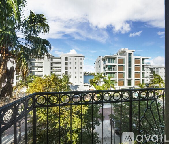 A balcony with a metal railing overlooks a body of water with buildings in the background.