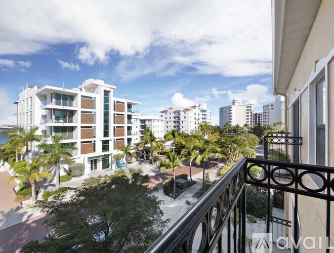 A balcony overlooks a courtyard with a building and trees.