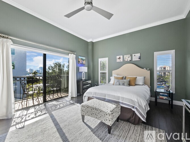 A bedroom with a large bed and a balcony with a view of the city.