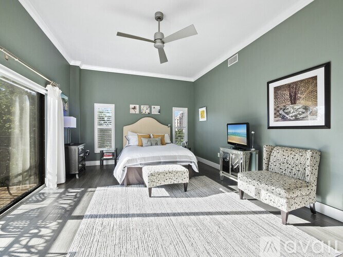 A bedroom with a bed, chair, and television.