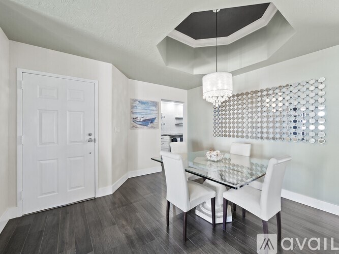 A dining room with a glass table and white chairs.