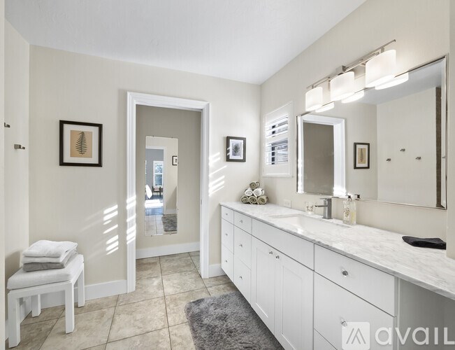 A bathroom with a white vanity and a white chair.