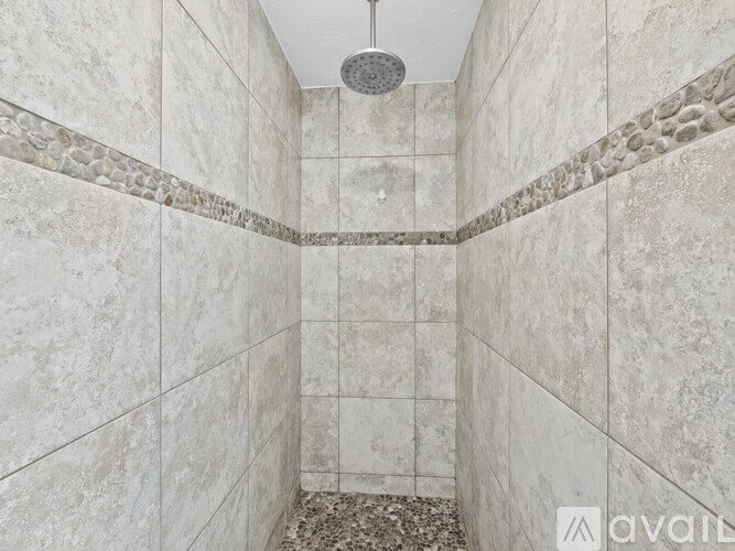 A shower area with a tiled floor and walls.