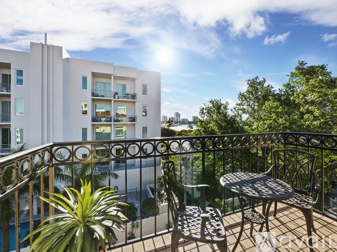 A balcony with a table and chairs overlooking a pool.