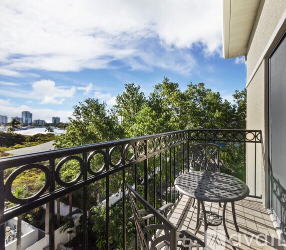 A balcony with a table and chairs overlooking a cityscape.