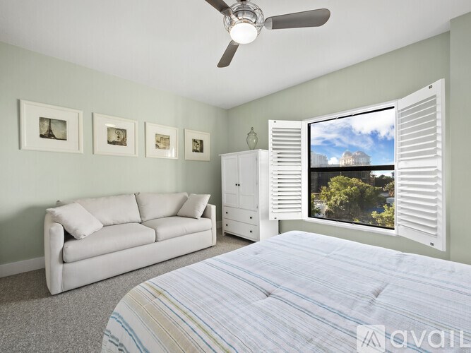 A bedroom with a bed, a couch, a dresser, and a ceiling fan.