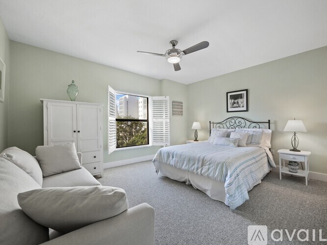 A bedroom with a bed, a chair, and a cabinet.