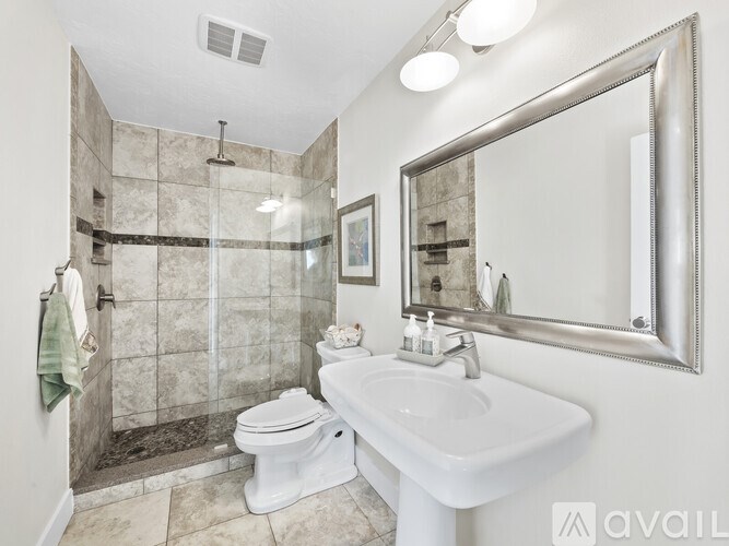 A bathroom with a toilet, sink, and mirror.